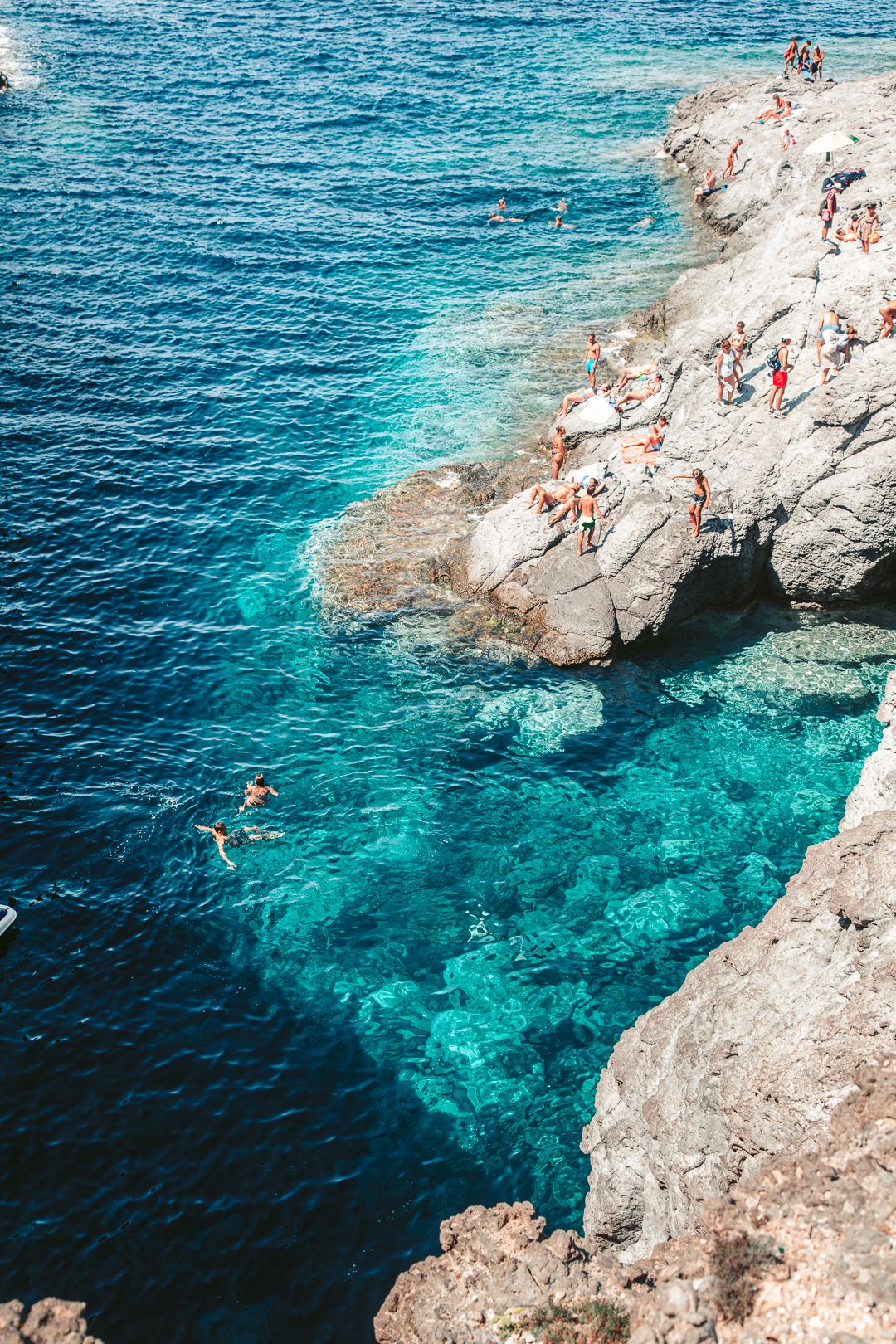 Swimmers in a turquoise cove between the rocks, Sardinia.