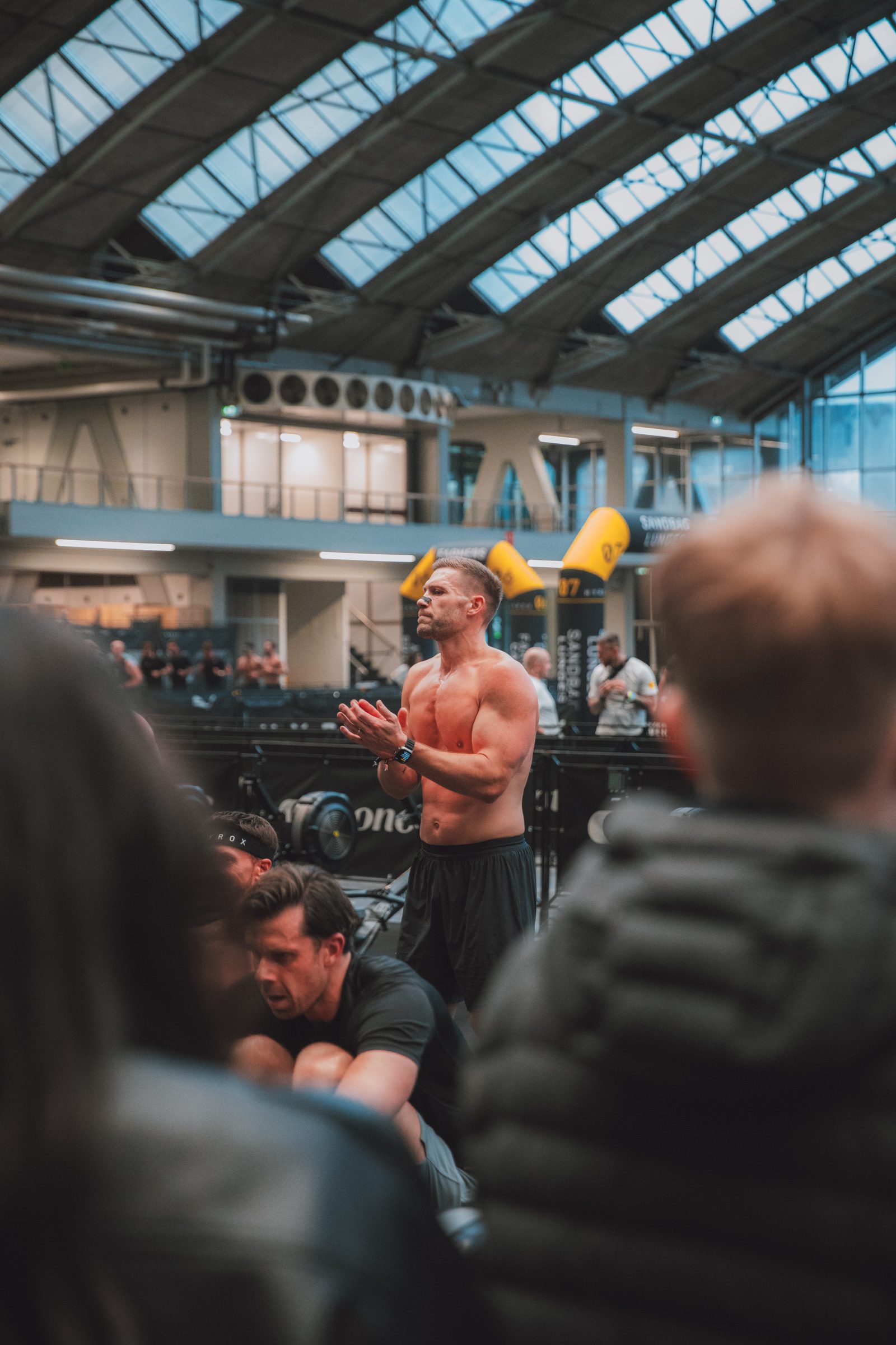 Clapping himself in through a foreground of blurred bodies.