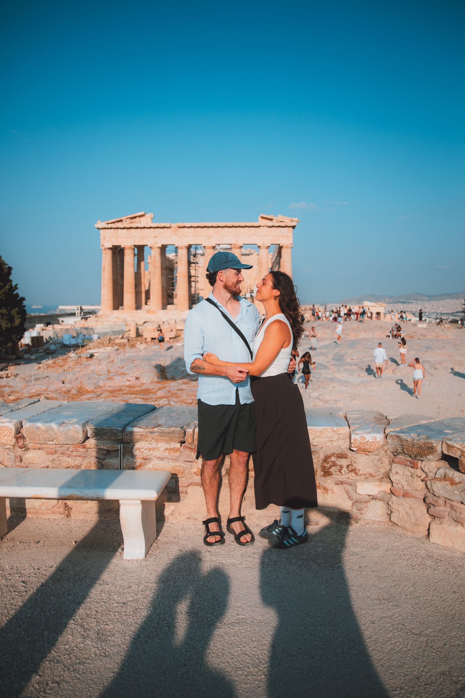 A couple wrapped up in each other in front of the Parthenon.