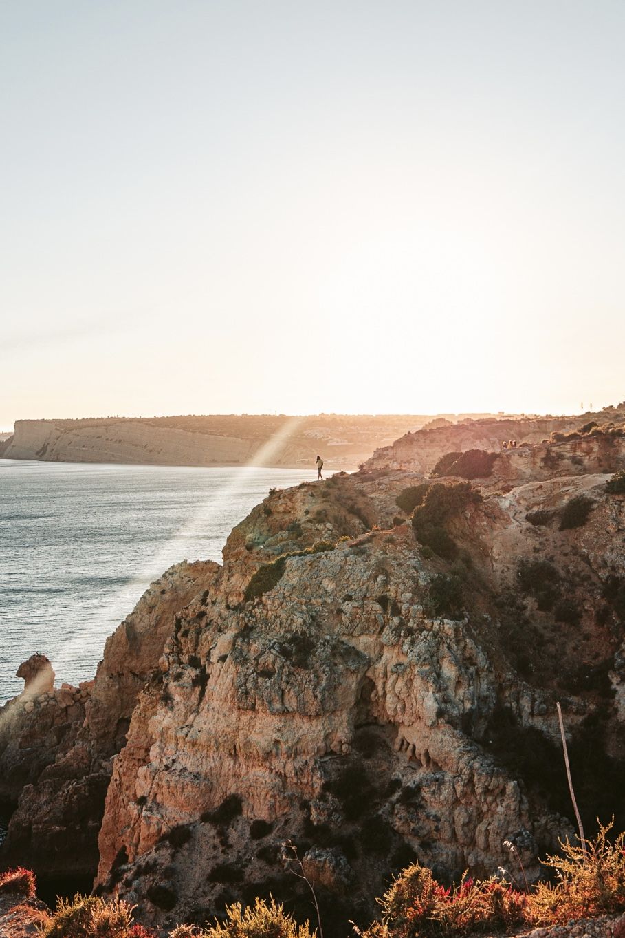 A ray of golden light over Algarve cliffs, one small figure at the edge.
