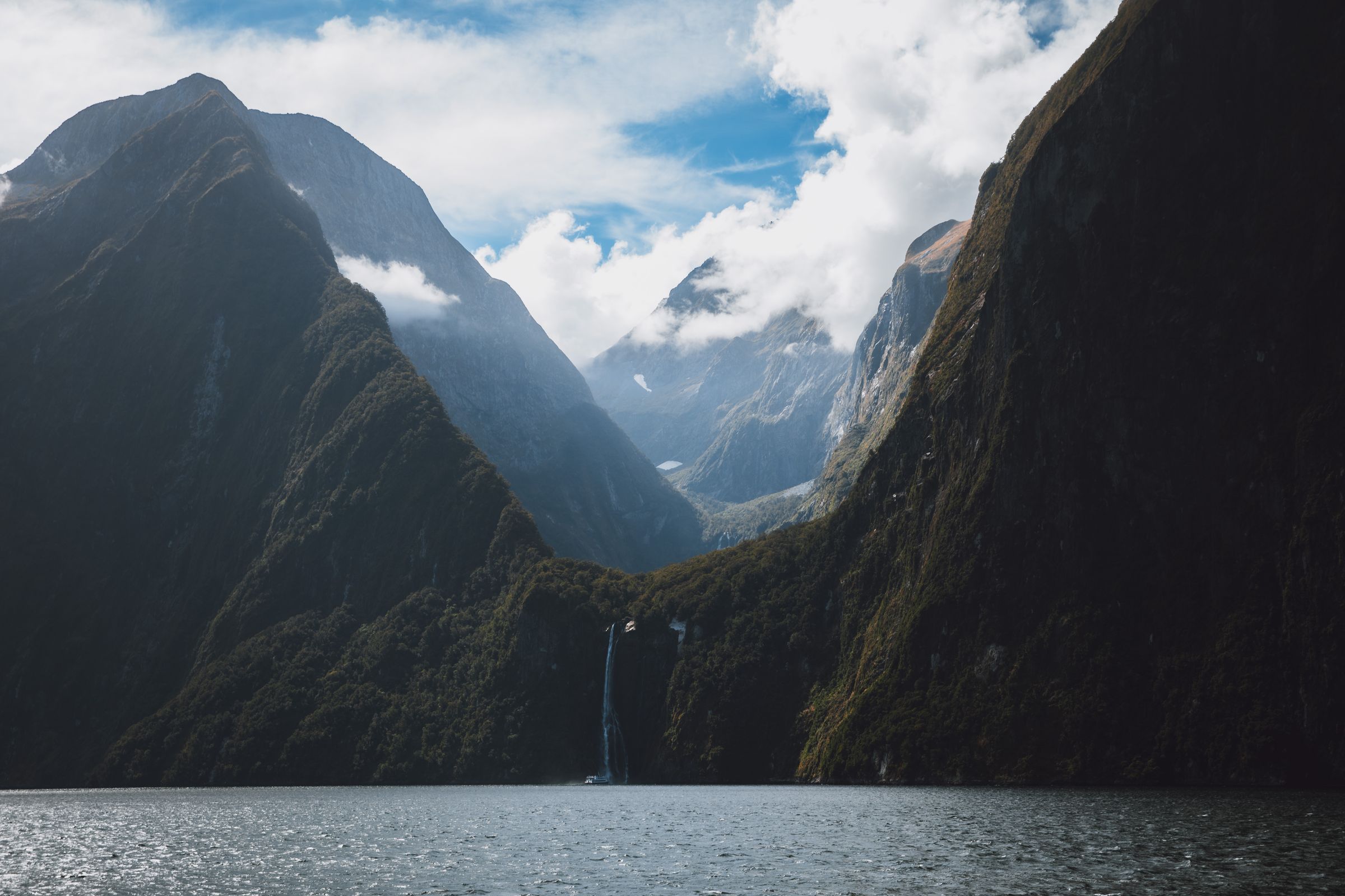 A waterfall pouring into Milford Sound between dark fjord walls.
